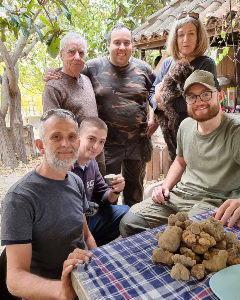 Real Truffle Hunters gathered around a table full of white truffles